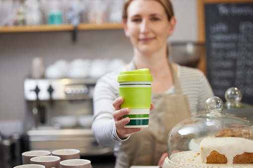 Trabajadora en café que sirve café en copa reutilizable sostenible photo