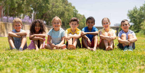 istock Happy children sitting on the green grass on day 1317829308