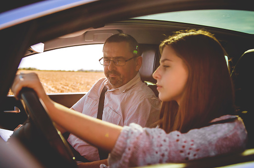 Man in the car giving basic lessons to teenage Girl driving