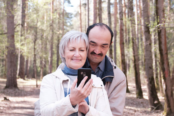 istock Elderly interracial couple park looking together at a mobile phone screen 1317833420
