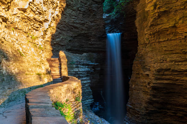 Cavern Falls at Watkins Glen State Park Early Morning Warm Sunlight Cavern Cascade Falls Over Gorge Trail Leading To Spiral Tunnel in Watkins Glen State Park seneca lake stock pictures, royalty-free photos & images