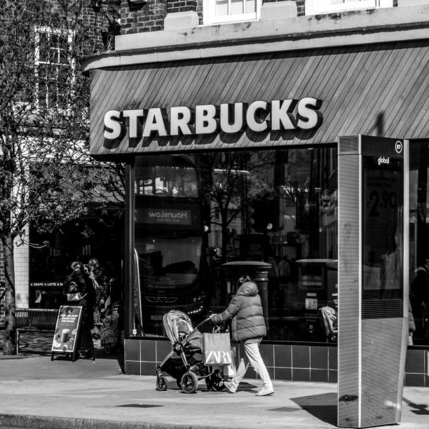 mujer caminando junto a una cafetería starbucks empujando un cochecito o cochecito de bebé - starbucks coffee coffee shop women fotografías e imágenes de stock