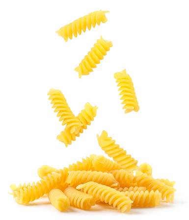 Spiral pasta falling on a heap close-up on a white background. Isolated