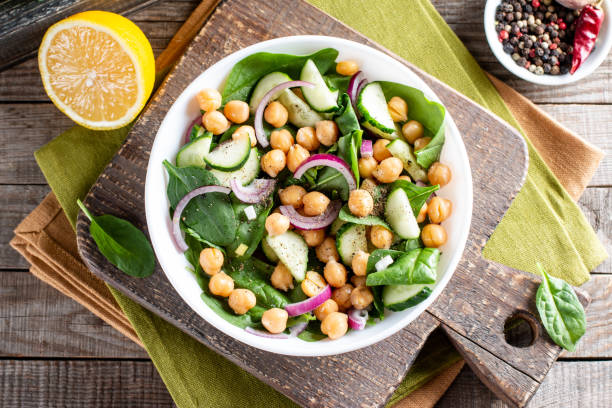Green vegetable salad with chickpea, spinach, cucumber, red onions, and greens on a table. Top view Green vegetable salad with chickpea, spinach, cucumber, red onions, and greens on a wooden table. Top view mediterranean food photos stock pictures, royalty-free photos & images