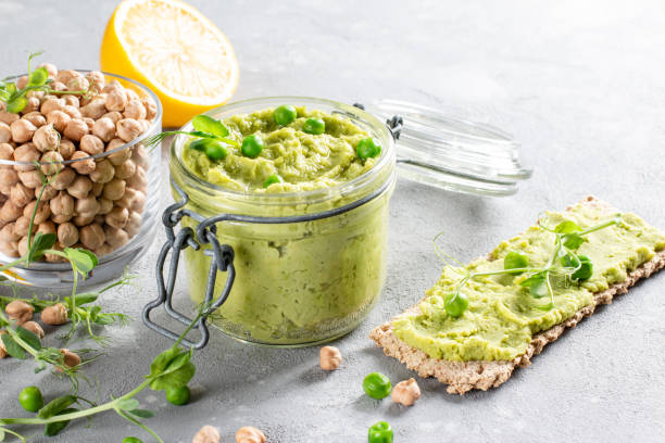 зеленый хумус петрушки с нутом, зеленым горошком и домашним нутом на столе. - avocado lemon snack cracker стоковые фото и изображения