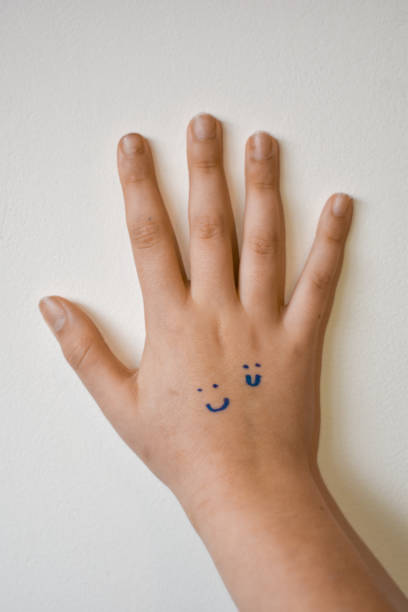 istock Girl's hand with smiley faces painted on her hand 1317843599