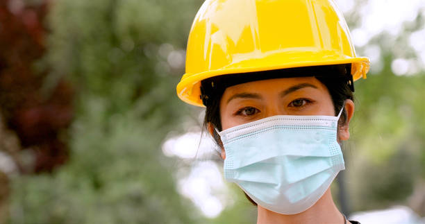 istock Mid adult female construction worker posing wearing a protective helmet and a protective mask 1317844643