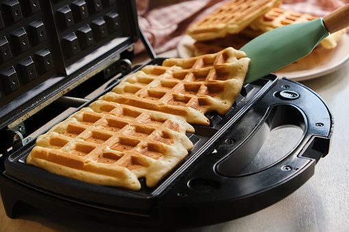 waffles are baked waffle iron machine. Belgian waffle dessert. Close up shot.
