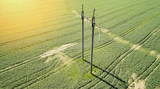 Electrical power line above drone view on green sunny meadow background