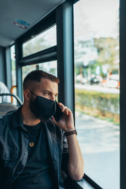 istock Young handsome man wearing protective mask and talking on his smartphone in a bus 1317851226