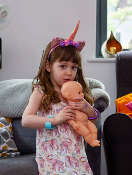 istock A Cute Baby Girl Sitting On A Sofa With A Doll 1317854920