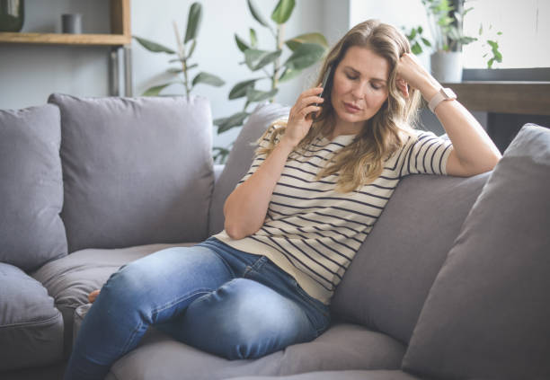 istock attractive middle aged woman sitting on the couch ( mobile phone,negative emotions) 1317856212