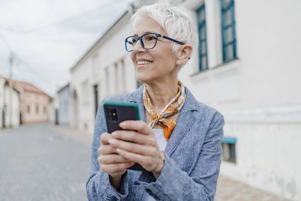 istock Senior woman is using mobile phone on the street 1317861743