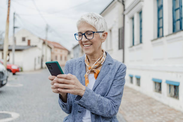 istock Senior woman is using mobile phone on the street 1317861744