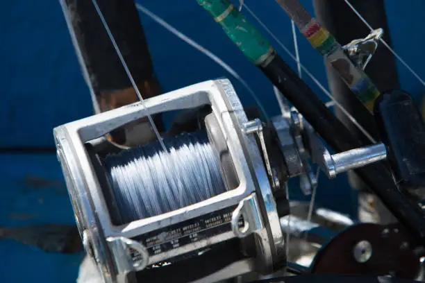 close up of fishing rod and reel stacked together on a boat