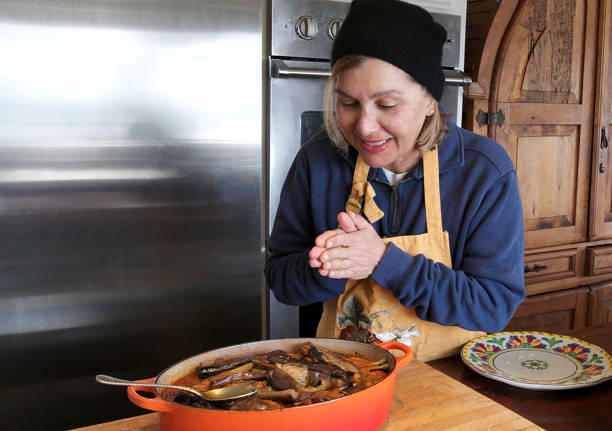 Brazilian cook in the kitchen offering a cooking pan with feijoada.