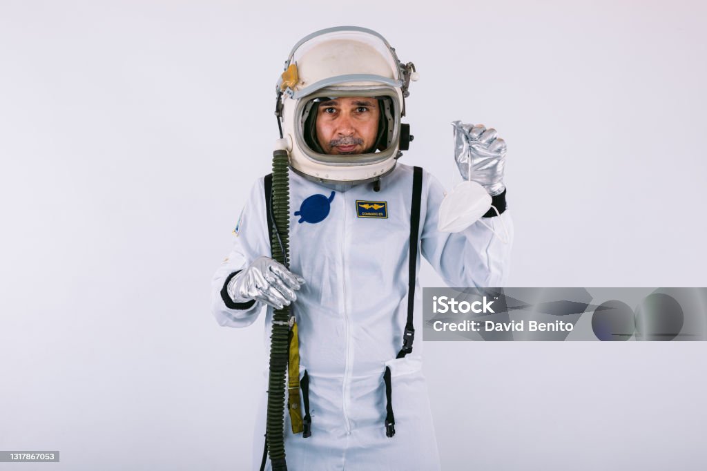 Male cosmonaut in spacesuit and helmet, holding a FPP2 mask, on white background. Covid-19 and virus concept 40-44 Years Stock Photo