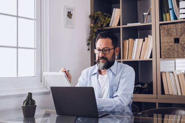 istock one young man working at home in the office with laptop and notebook taking notes talking in a video conference. One businessman calling communicating 1317872040