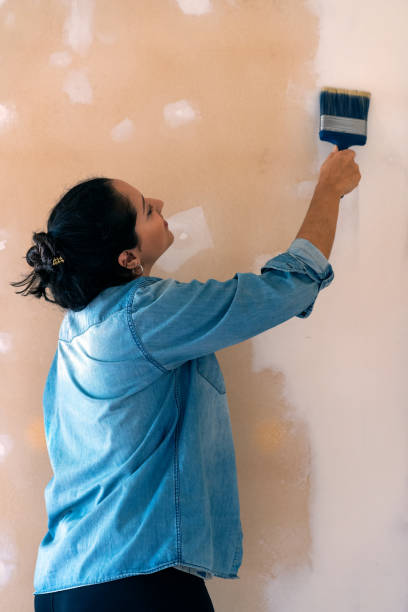 istock latin woman painting a wall and smiling. Renovation process. Copy space 1317878962