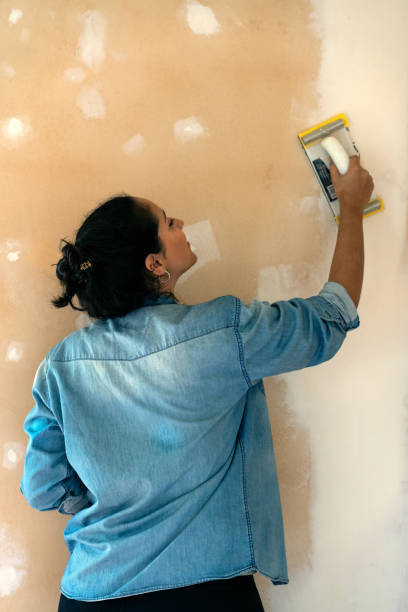 istock brunette woman smooths a plastering indoor wall with sandpaper. 1317878972