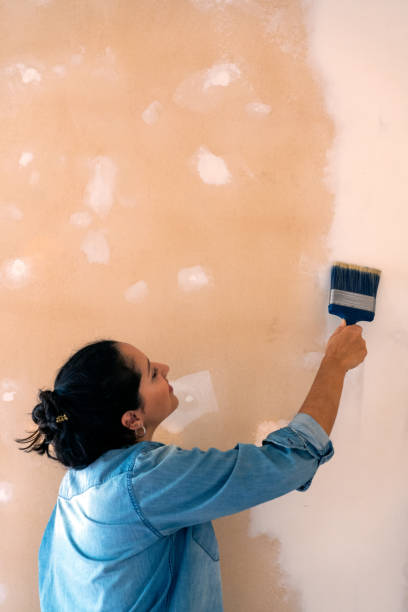 istock hispanic woman painting a wall and smiling. Renovation process 1317879061