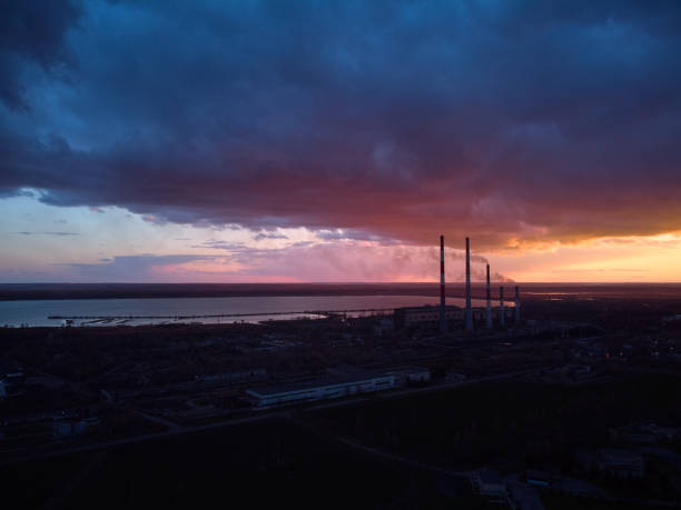 cheminées fumant d’une centrale thermique sur fond d’un ciel dramatique dans la soirée - factory night skyline sky photos et images de collection
