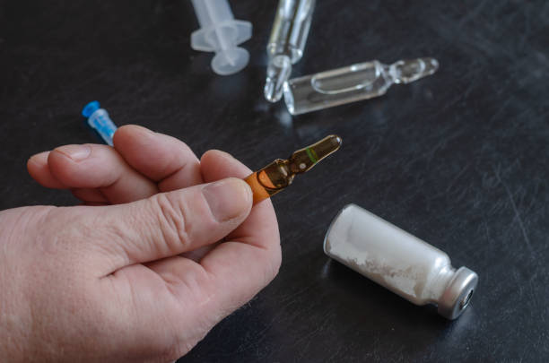 istock A hand, syringe, three vials, and bottle of white powder. 1317890927