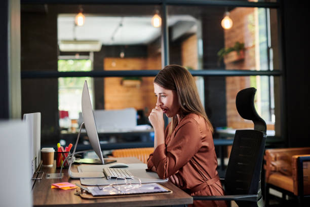 istock Shot of a young businesswoman yawning while using a computer in a modern office 1317890984