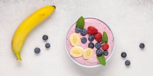 Smoothie bowl with banana and berries on grey background. Top view. Healthy food concept