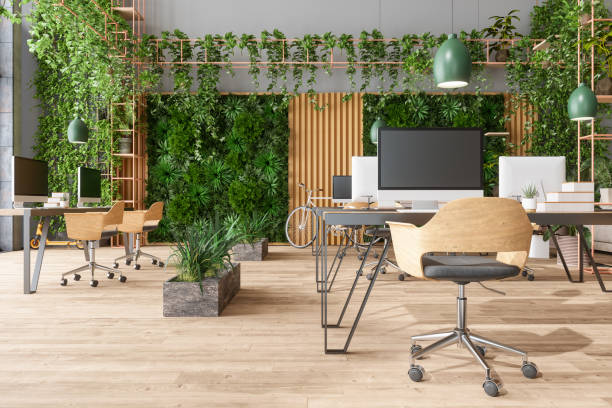 ufficio moderno a pianta aperta ecologico con tavoli, sedie da ufficio, luci a ciondolo, piante rampicanti e sfondo verticale del giardino - office furniture open plan desk foto e immagini stock