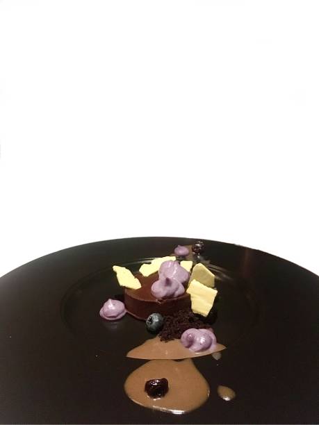 Black plated dessert dish with chocolate, blueberries and cream. White background. Black plated dessert dish with chocolate, blueberries and cream. White background. Copy space. plated chocolate dessert stock pictures, royalty-free photos & images