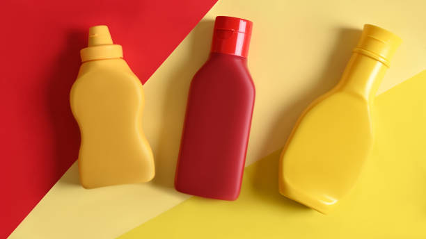 leigos planos. garrafas de molho em amarelo e ler fundo. - coloured bottles - fotografias e filmes do acervo