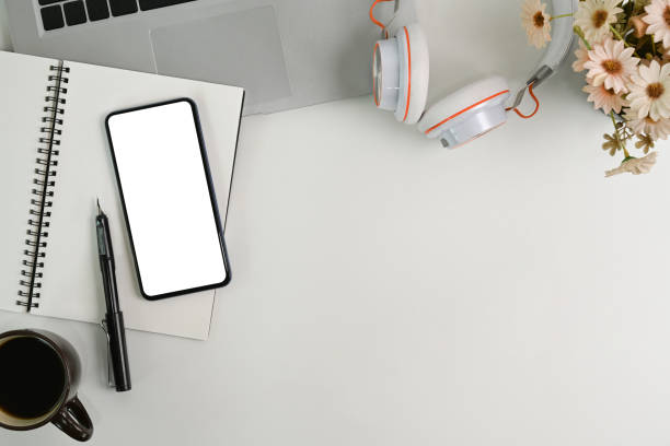 istock Mock up mobile phone, notebook, coffee cup and head phone on white office desk. 1317898565