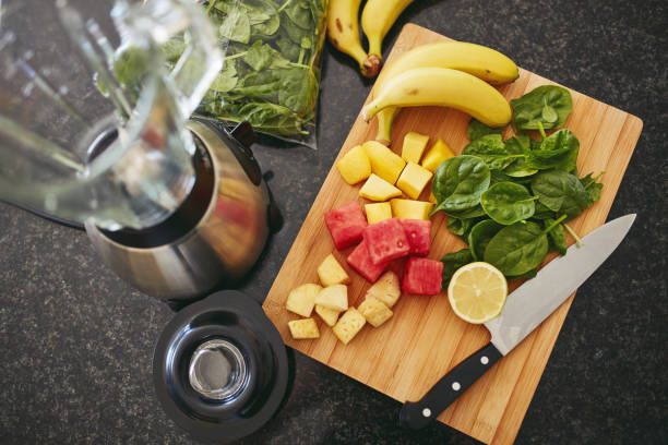 High angle shot of freshly cut fruit and a blender on a kitchen counter
