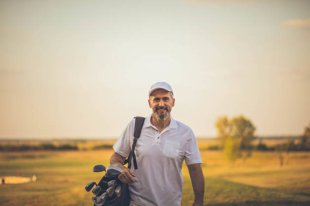 golfeur aîné heureux marchant sur le terrain de golf. la journée s’est parfaitement passée sur le terrain de golf. - action male only men mature men photos et images de collection