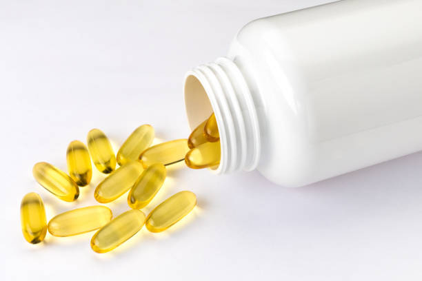 istock Omega 3 fish oil capsules out open container on white background 1317905275