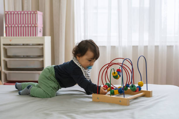 istock Cute toddler boy plays with a bead roller coaster in the bed at home 1317907614