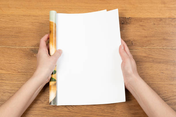 istock Woman's hands open empty catalog, magazines, book mockup on wooden table 1317909686