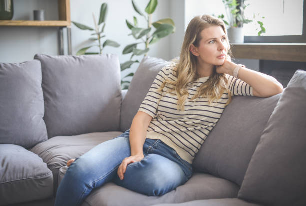 istock attractive middle aged woman sitting on the couch (negative emotions) 1317910472