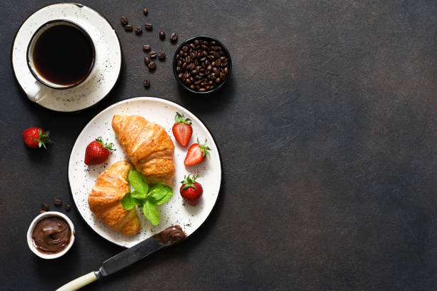 istock Croissant with chocolate paste and a cup of coffee, strawberries on the kitchen table. 