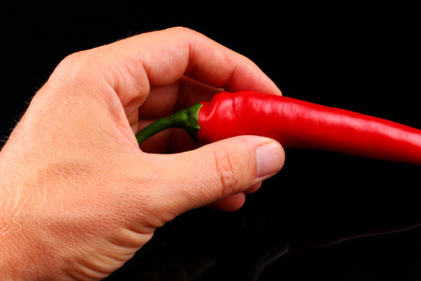 istock Red hot chili pepper in hand black background 1317916017