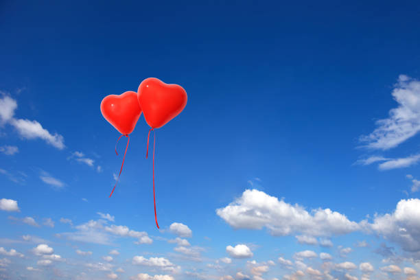 istock Two red heart-shaped balloons floating in a blue sky 1317916993
