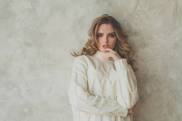 istock Stylish blonde woman in white woolen pullover on gray background 1317919037