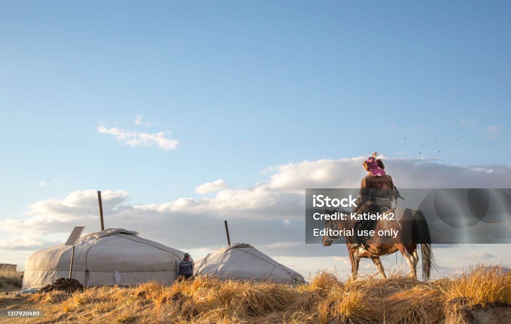 Mongolian nomad eagle hunter on his horse Bayan Ulgii, Mongolia, October 2nd, 2015: Old eagle hunter with his Altai Golden Eagle on his horse, going back home Independent Mongolia Stock Photo