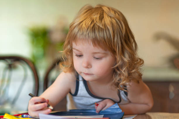 istock little curly boy draws with a colored pencil home 1317923417