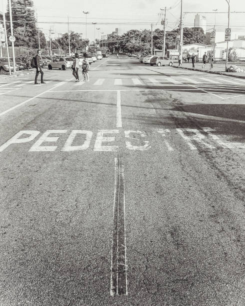 On an afternoon with no traffic, people cross the pedestrian crossing of an avenue. Mogi das Cruzes, Brazil, May 14, 2021