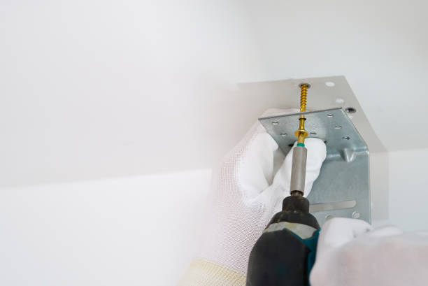 istock the master screws the metal corner to the concrete ceiling using a screwdriver, handyman 1317925177