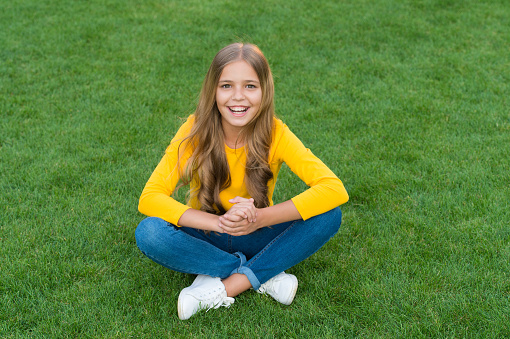 Happy smiling little girl relaxing green grass, excited child concept.