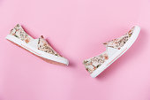 Pair of female's new stylish slip-ons with floral ornament on a pink background. Flat lay. Copy space. Side view of shoes