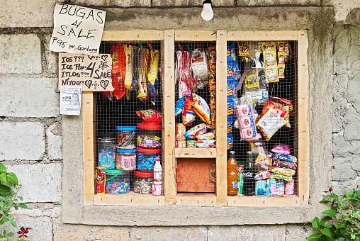 Grilled window functioning as a neighborhood sari-sari store in the Philippines. Sold are snacks, soft drinks, candies and groceries at a cheap price